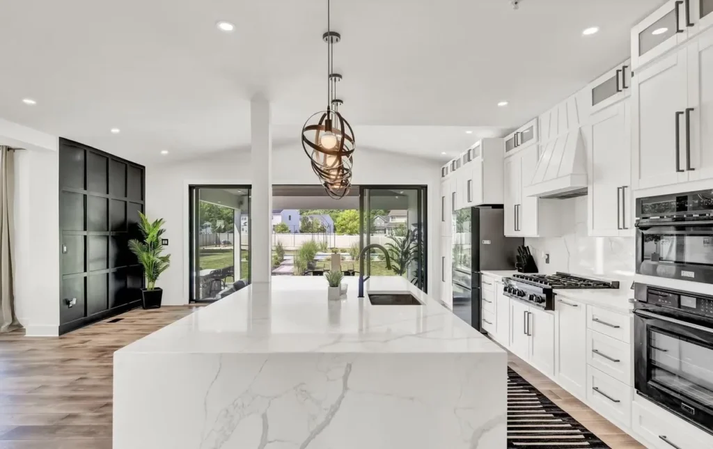 Finished home improvement project: open concept living space with kitchen in foreground featuring white cabinets and island