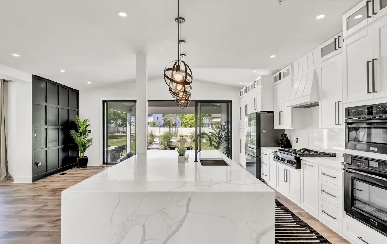 Finished home improvement project: open concept living space with kitchen in foreground featuring white cabinets and island